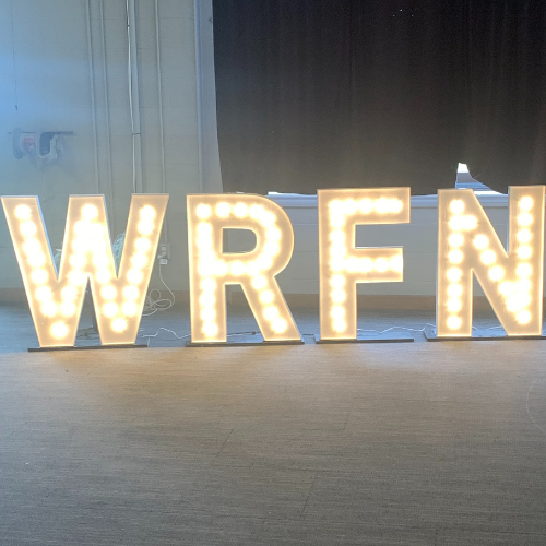 The image shows warm gold, illuminated marquee letters that spell out "WRFN"